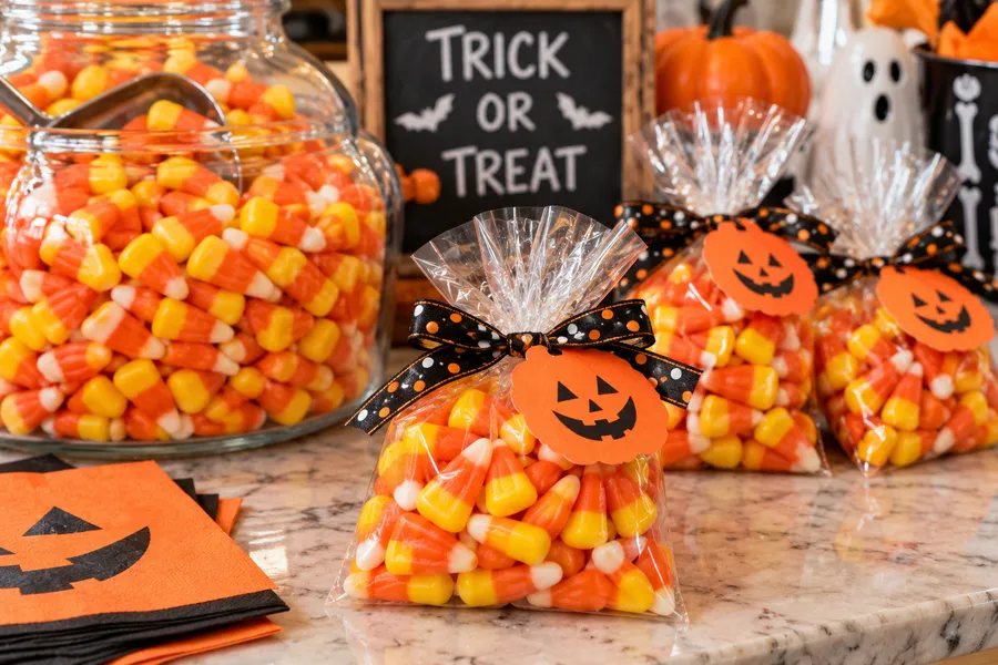 Clear favor bags of candy corn tied with Halloween ribbon and pumpkin tags